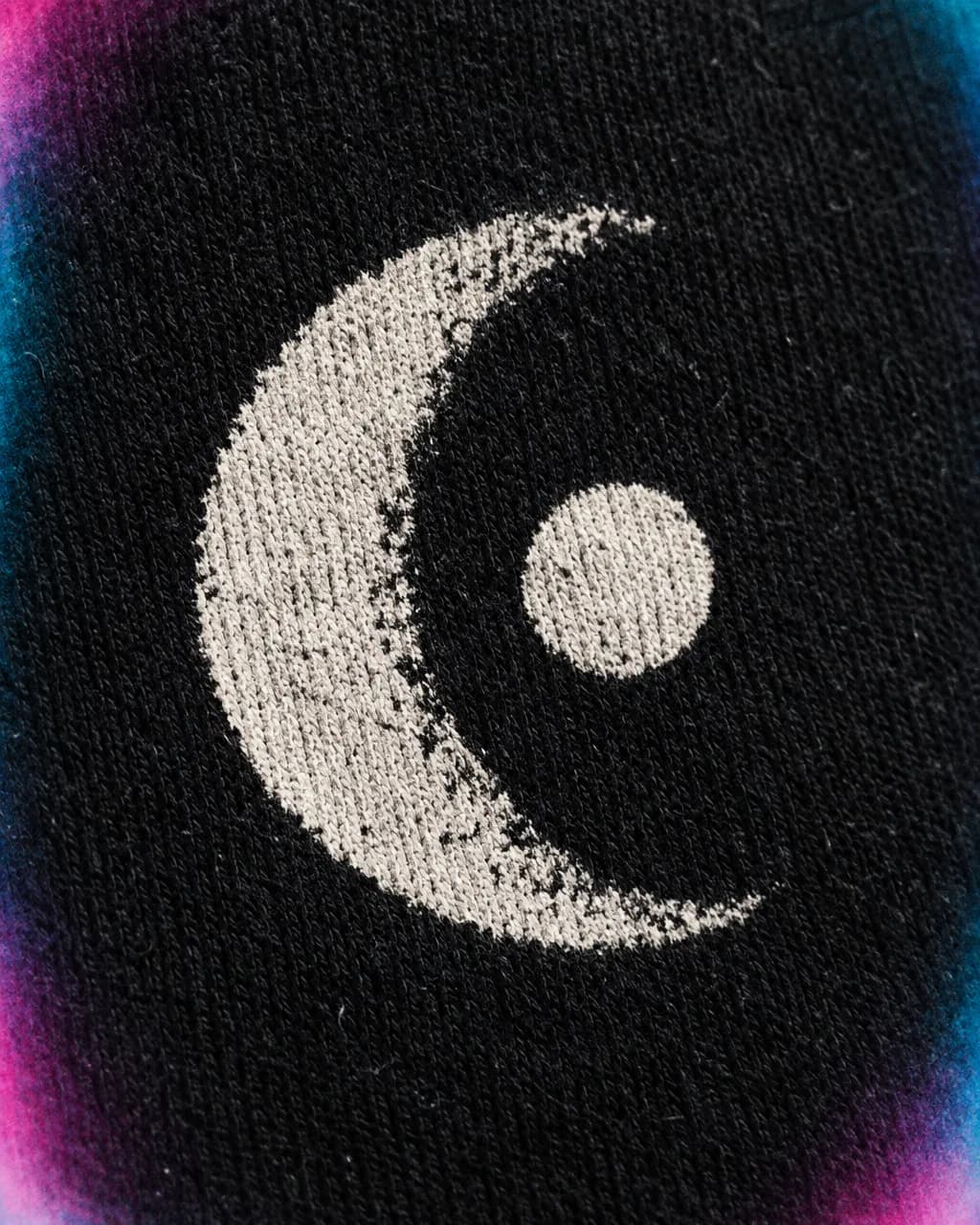 Close crop of a white moon-and-dot print sitting on black cotton fabric