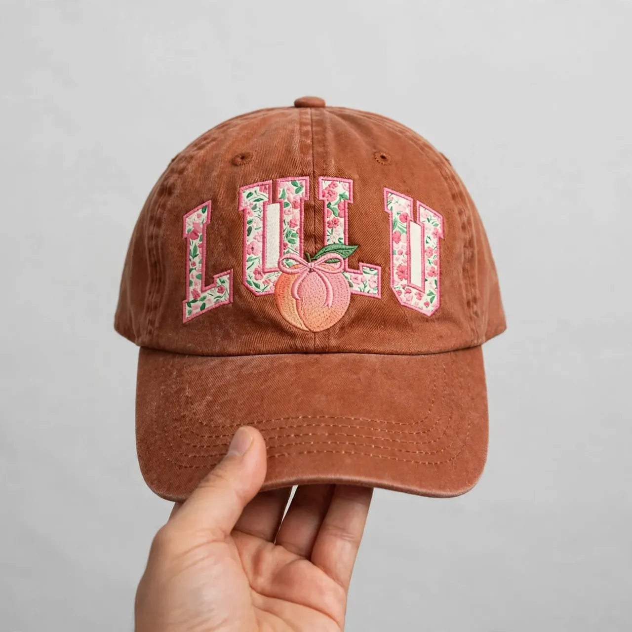 Washed-rust dad cap held up against a studio backdrop