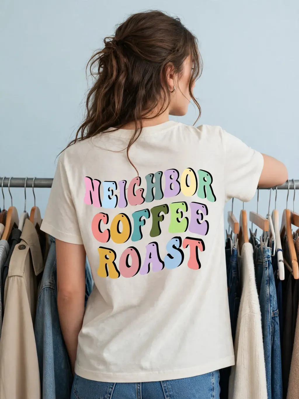 Model wearing a pastel back-print tee by a clothing rail