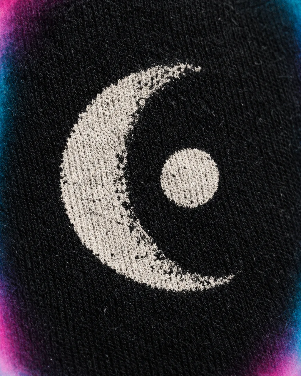 Close crop of a white moon-and-dot print sitting on black cotton fabric